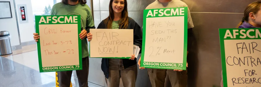 Oregon AFSCME Research Worker holding signs. 